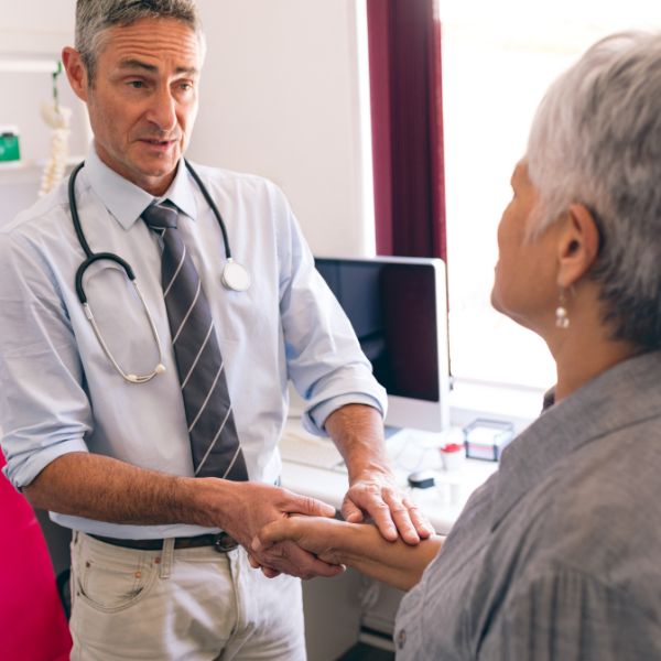 doctor with stethoscope around neck shakes hand of patient