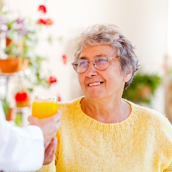 woman looks at person handing her a glass of OJ