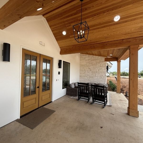 covered porch of Silver Elite Senior Care featuring natural wood ceilings, rocking chairs, and stone accents