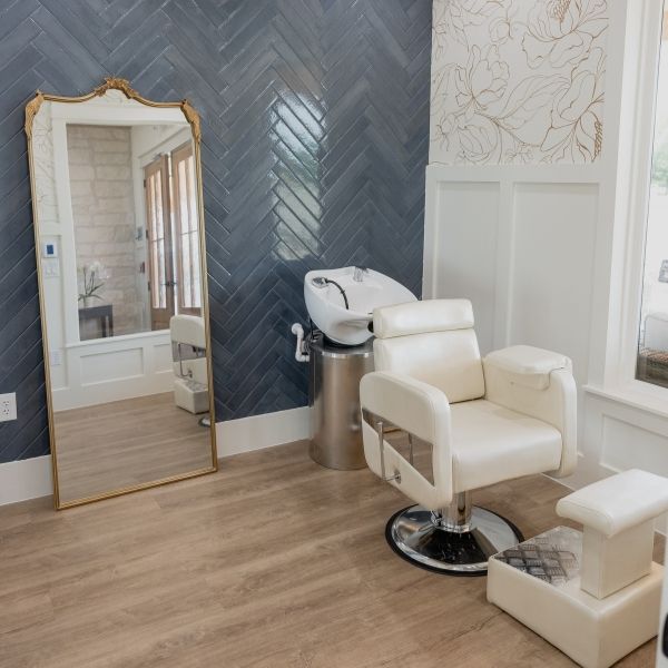 The onsite professional hair salon in an assisted living facility featuring boutique styling chairs, herringbone tile, and gold-framed mirrors.