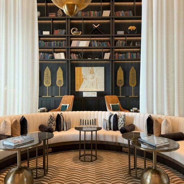An elegant, boutique common area featuring luxury curved seating, high ceilings, and a designer library wall at a private Clearwater senior estate.